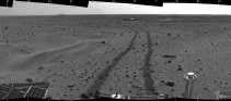 Spirit kijkt achterom naar zijn sporen in het marszand. In de verte is nog het landingsplatform van de marsjeep te zien. Nasa <br><br><!--para1--><br><br><!--para2-->