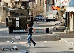 Een Palestijnse jongen vlucht weg voor een van de Israëlische tanks gisteren in Tulkarem.