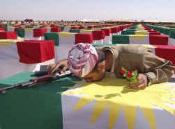 Een Koerdische strijder kust de kist van een van zijn volksgenoten die gevonden werden in een van de vele massagraven en deze herbegraven werden in Arbil.