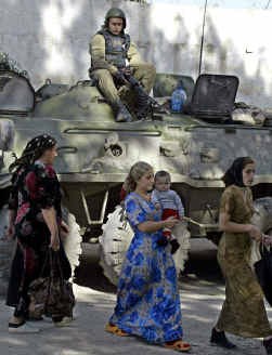Tsjetsjeense vrouwen stappen voorbij een Russische soldaat in Kurchaloi. Het conflict in Tsjetsjenië begon niet als een religieus geïnspireerde strijd.