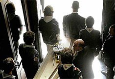 Scoutsvrienden dragen de kist van Joe Van Holsbeeck naar buiten na de uitvaartdienst.