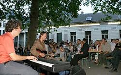 Gewoon een man op een stoel met een gitaar, terwijl aan de andere kant van de kerk de decibels van het podium golven.fvv