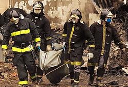 Brandweermannen dragen de stoffelijke resten van een slachtoffer weg. 186 passagiers en bemanningsleden bevonden zich aan boord van het vliegtuig. Ze kwamen allen om het leven.ap<br>