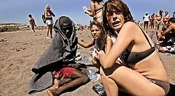 Toeristen bij een uitgeputte Afrikaanse illegale migrant op een strand op het Spaanse eiland Tenerife. ap<br>
