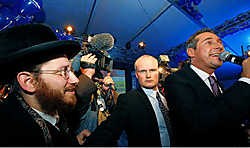 Een orthodoxe joodse man die na de verkiezingen in de buurt van Heinz-Christian Strache (rechts) tracht te komen, wordt tegengehouden door een van diens bodyguards.afp<br>