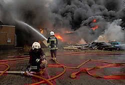 Een brandweerman probeert het lek in een van de brandslangen te stoppen. De brandweer stelde alles in het werk om een ontploffing te vermijden. belga<br>