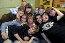 Gina Rogiers in een groepsknuffel met haar gastgezinsleden. Vooraan ligt Frederic, dan van links naar rechts Jochen, Simon, Gina, Mike, Inaki, Geoffrey en Nicolas. Achteraan Gina's echte gezin: echtgenoot Marc en dochter Othilly.