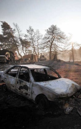 Een uitgebrande woning en wagen in Agios Stefanos.afp