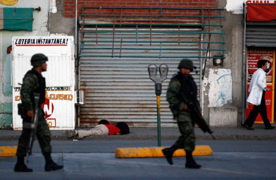 Mexicaanse soldaten patrouilleren voorbij het lijk van een neergeschoten man in Ciudad Juarez.reuters