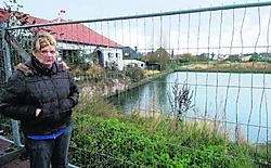 Carine toont de bouwput die er de oorzaak van is dat haar huis nu onbewoonbaar is. vln