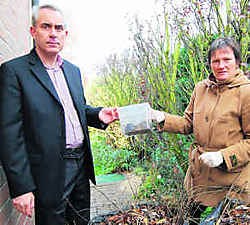 Walter Huts en Els Struyven tonen een potje vol asbestvezels. Dat vonden ze tussen de struiken, nà de opruiming. ibo