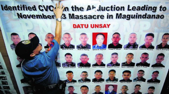 Een politieman hangt een affiche op met de foto's van honderd gezochte leden van de Ampatuan-militie, die beschuldigd wordt van politieke moorden. afp