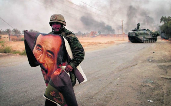 Een Amerikaanse soldaat verscheurt een poster van Saddam in Irak in 2003. De VS en Groot-Brittannië verdachten Irak van het bezit van massavernietigingswapens en vielen het land officieel daarom aan. photo news