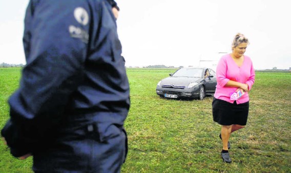 Een vrouw van de Franse zigeunergroep verlaat het terrein in Wingene terwijl de arm der wet toekijkt. 'Het racisme is overal', vindt hun internationale leider Mario Holderbaum.Jorge Dirkx/belga