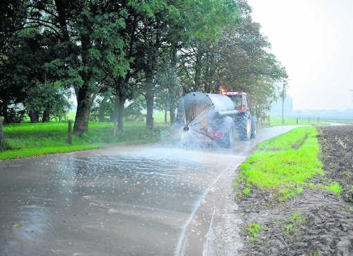 Landbouwer Wouter Claerbout spuit de modder na de oogst van de weg. fmr