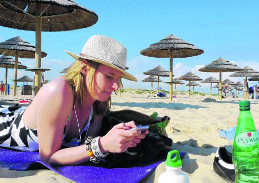 Op een Portugees strand lekker lui met je gsm internetten, is vandaag erg duur.Inge van Mill/Hollandse Hoogte