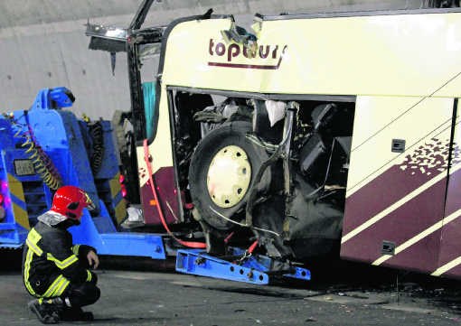 Een brandweerman inspecteert het wrak van de bus dat wordt getakeld.Denis Balibouse/reuters