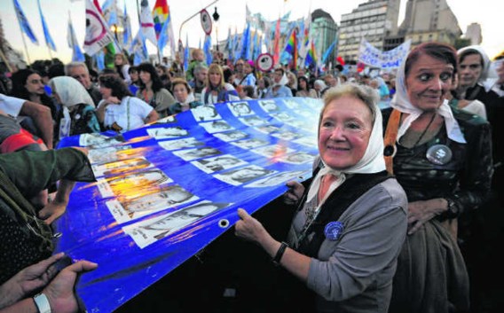 De grootmoeders van de Plaza de Mayo dragen een grote vlag met de portretten van de vermiste kinderen.