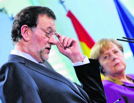 Angela Merkel werpt Mariano Rajoy een strenge blik toe.