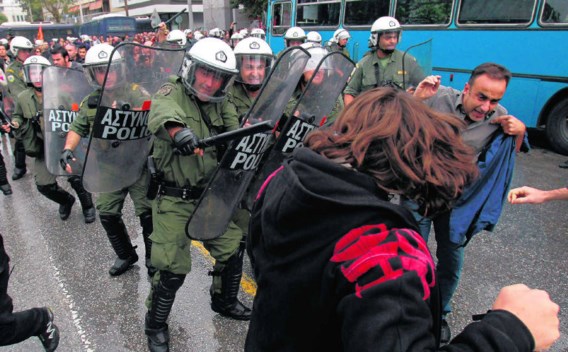 De oproerpolitie in Thessaloniki jaagt betogers weg die tijdens een militaire parade tegen de bezuinigingen protesteren.