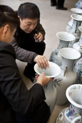 De mogelijke Chinese kopers inspecteren kritisch de vazen.
