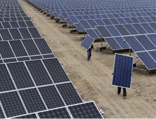 Arbeiders dragen zonnepanelen in een energiecentrale in Xinjiang. Chinese zonnepanelen zijn kunstmatig goedkoop, zeggen critci. 