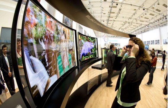 Het is een maar al te bekend huiselijk drama: het gevecht om de zeggenschap over wat op de kijkbuis verschijnt – of dus het gevecht om de afstandsbediening. De Zuid-Koreaanse technologiereus Samsung stelde gisteren op de Berlijnse IFA-beurs een ingenieuze oplossing voor: een gebogen televisietoestel waarop tegelijkertijd twee programma’s bekeken kunnen worden. Dankzij een 3D-brilletje – met ingebouwde luidsprekers – kan het gewenste beeld gefilterd worden. Zo kan de ene partner probleemloos van een romantische komedie genieten, terwijl de andere supportert voor zijn favoriete voetbalploeg. Dat de een juicht bij een doelpunt, terwijl de ander een traantje wegpinkt bij een vaarwelkus, moet dan maar als een klein ongemak gezien worden. Samsung brengt zijn kromme S9C-tv aan de man voor 7.999 euro.