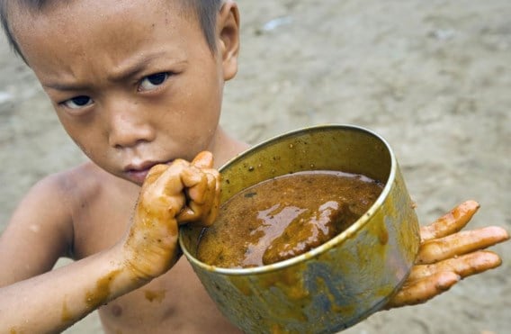 Dit jongetje uit Myanmar toont het blik waarmee hij heel de dag melasse moet ophalen.