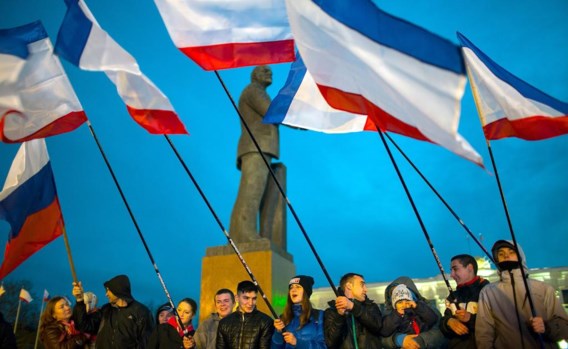 Mensen zwaaien met de vlag van de Krim op het Leninplein in Simferopol.