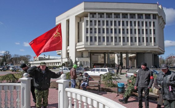 Een man zwaait met een Sovjetvlag voor het parlement in Simferopol.