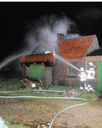 De brandweer verhinderde dat de stookolietank naast het gebouw in brand vloog.