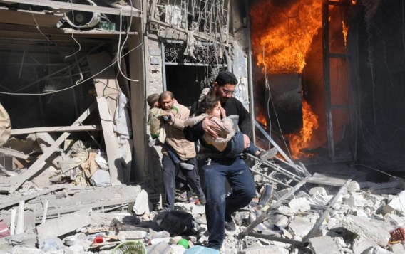 Twee mannen redden kinderen uit een brandend gebouw na een bombardement met ‘barrel bombs’.