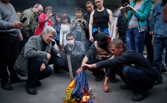 Pro-Russische betogers verbranden een Oekraïense vlag voor een districtgebouw in de Oost-Oekraïense stad Donetsk.