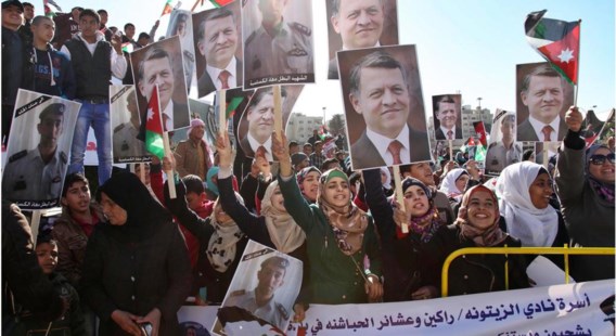 Betogers in Amman, zwaaiend met foto’s van koning Abdullah II en van piloot Moaz Kasasbeh.