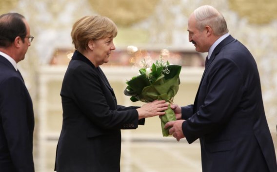 De Wit-Russische president Loekasjenko bedacht Angela Merkel met een bos witte bloemen. Zij twijfelde tussen een te strenge en een te vriendelijke blik.