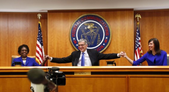 Voorzitter Tom Wheeler van de Federal Communications Commission begroet twee commissieleden aan het begin van de zitting over netneutraliteit.