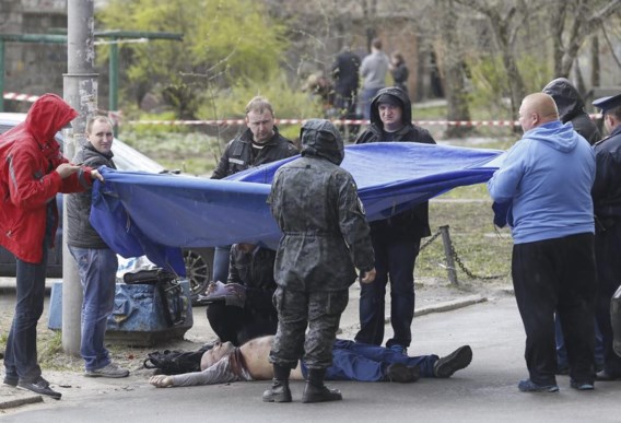 Politiemannen  inspecteren het lijk van  de op straat omgebrachte journalist Oles Buzina.  