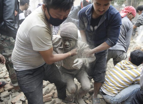 Reddingswerkers bevrijden een man van onder het puin van een gebouw in Kathmandu.