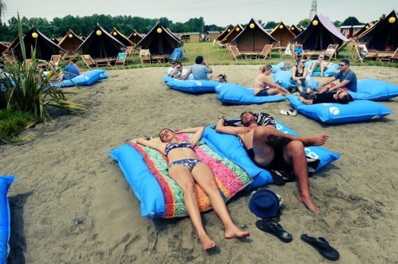 <p>Ze zijn net zo uitgeput als de andere bezoekers, maar dankzij het comfortabele kussen kunnen deze jongeren twee vliegen in één klap slaan: hun roes uitslapen, en genieten van de zon. <span class="credit">Koen Bauters</span></p>