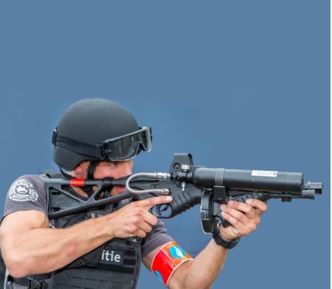 Een lid van het Snelle Respons Team demonstreert een ‘less lethal’ wapen dat kunststof projectielen afvuurt.