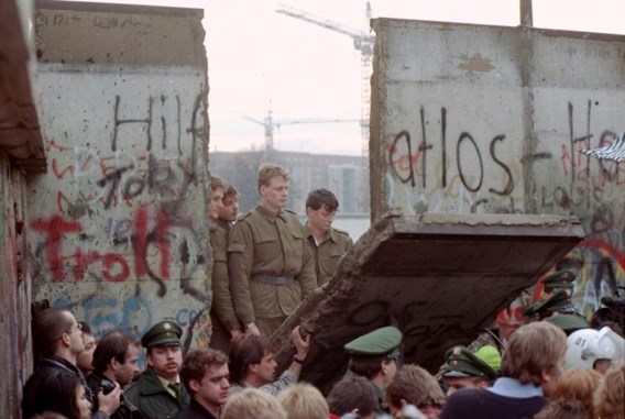 Oost-Duitse grenswachters kijken door een bres in de Berlijnse Muur op 11 november 1989.