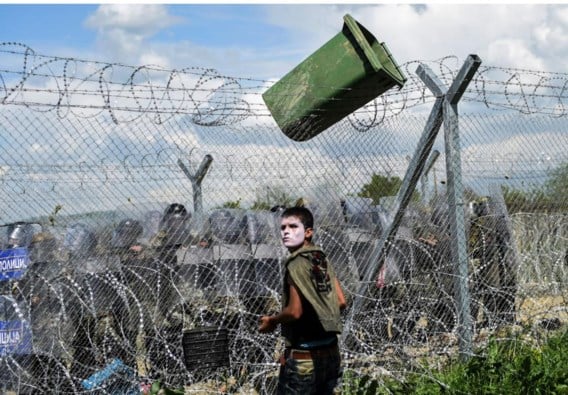 Een migrant staat tegenover de Macedonische politie nabij de Griekse grensstad Idomeni.