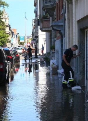 Een brandweerman legt een zandzakje op een keldergat.