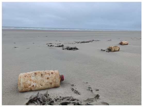 Na storm Odette: honderden flessen motorolie uit 1966 op stranden aangespoeld