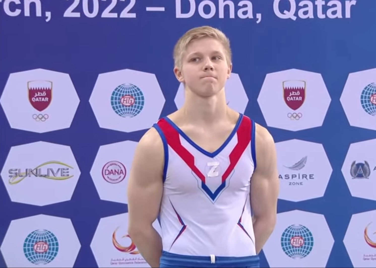 Российская гимнастка поднимается на пьедестал с Z на груди рядом с украинкой