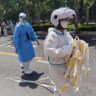 Een gezondheidsmedewerker haalt een lint weg dat het  cordon moest afbakenen bij een covid-uitbraak in Shanghai. 