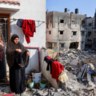 Een Palestijnse vrouw hangt de was op bij haar beschadigde woning in Gaza-Stad.  