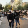 Vrouwelijke demonstranten worden uiteen­gejaagd in Teheran. 