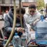 Burgers van Mykolajiv vullen hun plastic flessen met drinkwater uit de  grote tonnen in de stad. 