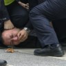 Politiemannen houden een man in bedwang tijdens een betoging zondag in Shanghai. 